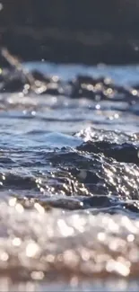 Calming ocean waves flow over rocks at the shore, capturing serene coastal beauty.