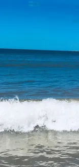 Scenic mobile wallpaper of ocean waves with blue sky and white surf.