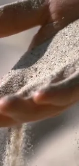 Serene wallpaper of sand flowing through hands.