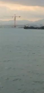 Serene seascape with ship and cranes under a cloudy sky.