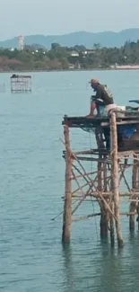 Fisherman on a wooden pier over calm blue waters at the seaside.