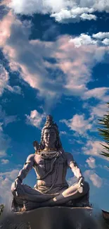 Shiva statue meditating beneath a vibrant blue sky with clouds.