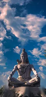 Serene Shiva statue under a vivid blue sky with fluffy clouds.