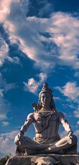 Statue of Lord Shiva meditating under a vivid blue sky with fluffy clouds.