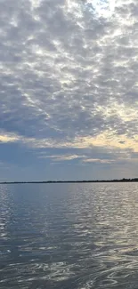 Calm ocean view with cloudy sky reflecting on the water.