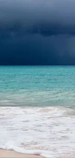 Stormy beach with turquoise water and dark clouds in the distance.