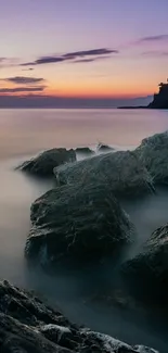 Tranquil beach sunset with rocks and a pastel sky.