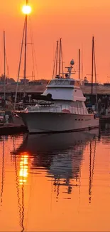 Serene harbor at sunset with boats and orange sky reflection.