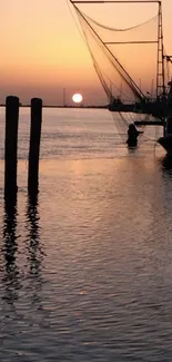 Silhouetted harbor at sunset with fishing boats and orange sky.