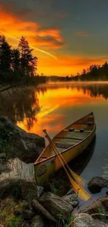 Canoe at sunset on a tranquil lake with vibrant orange sky and serene surroundings.