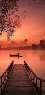 Serene sunset over a lake with a silhouetted boat and vibrant orange sky.