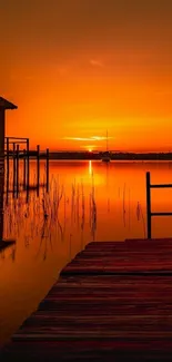 Sunset over tranquil lake with orange sky and dock.