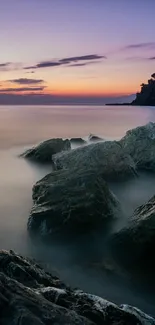 Serene sunset over rocky ocean shore, calm waters reflecting twilight hues.