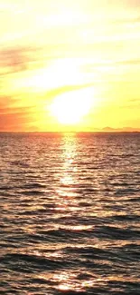 Serene sunset over calm ocean with rocky shoreline.