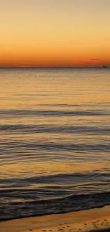 Serene ocean view at sunset with orange sky and calm waters.