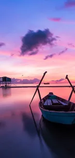 Serene sunset over water with a lone boat and vibrant pink sky.