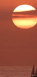 Orange sunset over ocean with sailing boats in view.