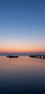 Tranquil sunset view with pier silhouette over calm ocean.
