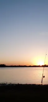 Tranquil sunset over calm water with fishing in the foreground.