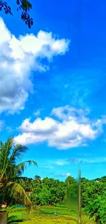 Bright blue sky with clouds over green tropical landscape.