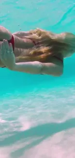 Woman swimming underwater in turquoise seas.