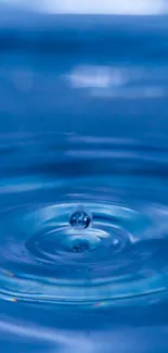 Close-up of a water droplet creating ripples on a blue surface.