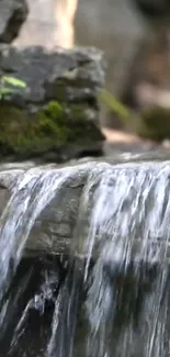 Tranquil waterfall over mossy rocks in mobile wallpaper.