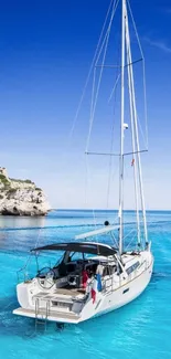 A yacht sailing on bright blue waters under a clear sky, with rocky cliffs nearby.