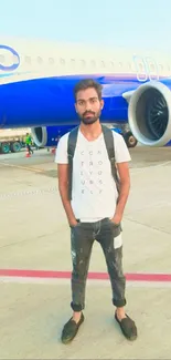 Traveler standing by a blue plane on the airport runway.