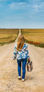 Woman walking on a country road with suitcase under a clear blue sky.