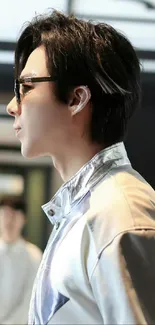 Side profile of a person wearing sunglasses in a stylish outfit.