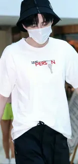 Person wearing a white t-shirt, black bucket hat, and mask.