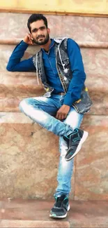 Young man in blue shirt and denim jeans posing stylishly.