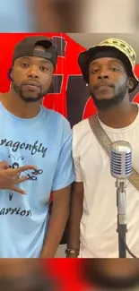 Two stylish men with a microphone and red background.