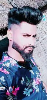 Man in floral shirt posing outdoors with stylish hair and beard.