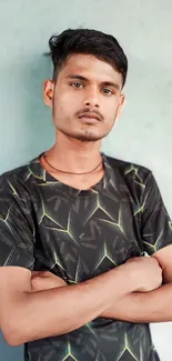 Young man in a geometric-patterned shirt standing confidently.