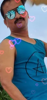 Man in blue tank top with colorful heart pattern background.