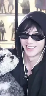 Hooded person with sunglasses holding a fluffy dog.