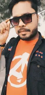 Cool man wearing sunglasses and an orange shirt with a unique logo.