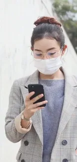 Woman with smartphone and mask in a minimalistic, modern urban setting.