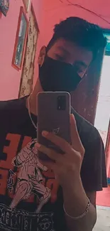 Mirror selfie with a black mask and pink room background.