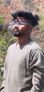 Stylish man with glasses in natural setting, wearing beige top.