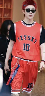 Person in red basketball outfit with sunglasses on street.