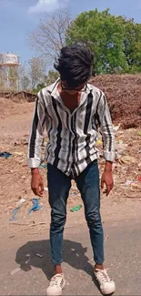 Young man in striped shirt and jeans on street, urban fashion.