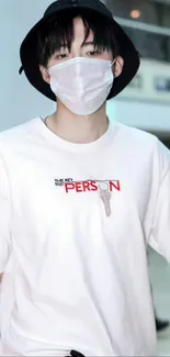 Person in white T-shirt and black hat with face mask, trendy streetwear style.