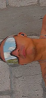 Man with reflective sunglasses and tattoos lounging.