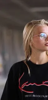 Blonde wearing glasses in urban setting with graphic tee.