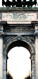 Triumphal arch with sculptures at sunset.