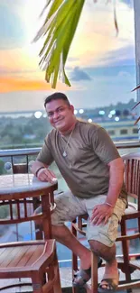 Man enjoying tropical sunset on a balcony with chairs.