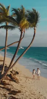 Couple walking on tropical beach with palm trees and ocean.